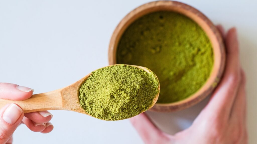A spoon full of Moringa powder in a person's hand