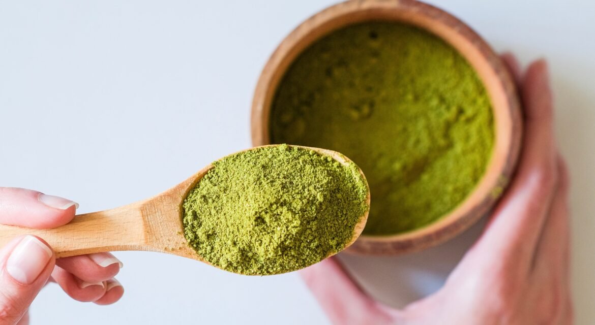 A spoon full of Moringa powder in a person's hand