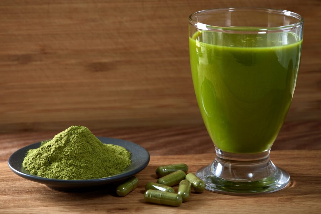Capsules filled with Moringa powder and moringa juice on wooden background